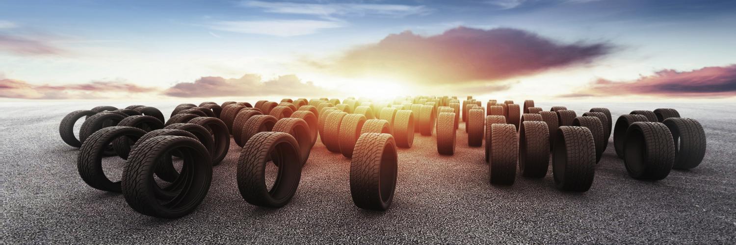 a lot of tires on pavement with a sunset in the background
